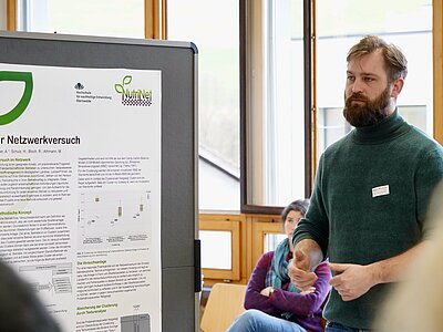 Mann steht vor einem Flipchart mit einem Poster.