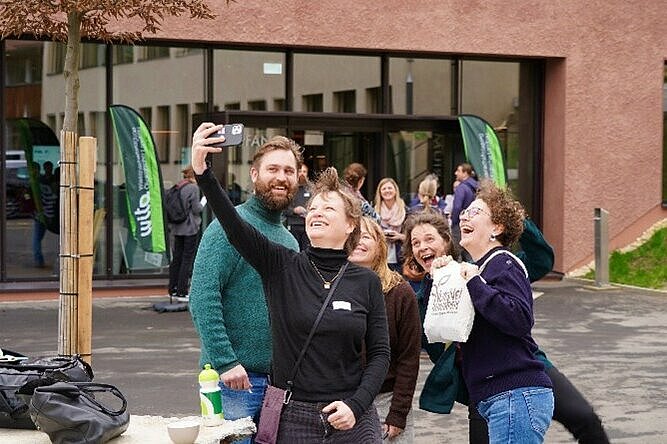 Gruppe von Personen lacht und macht ein Selfie mit dem Handy.