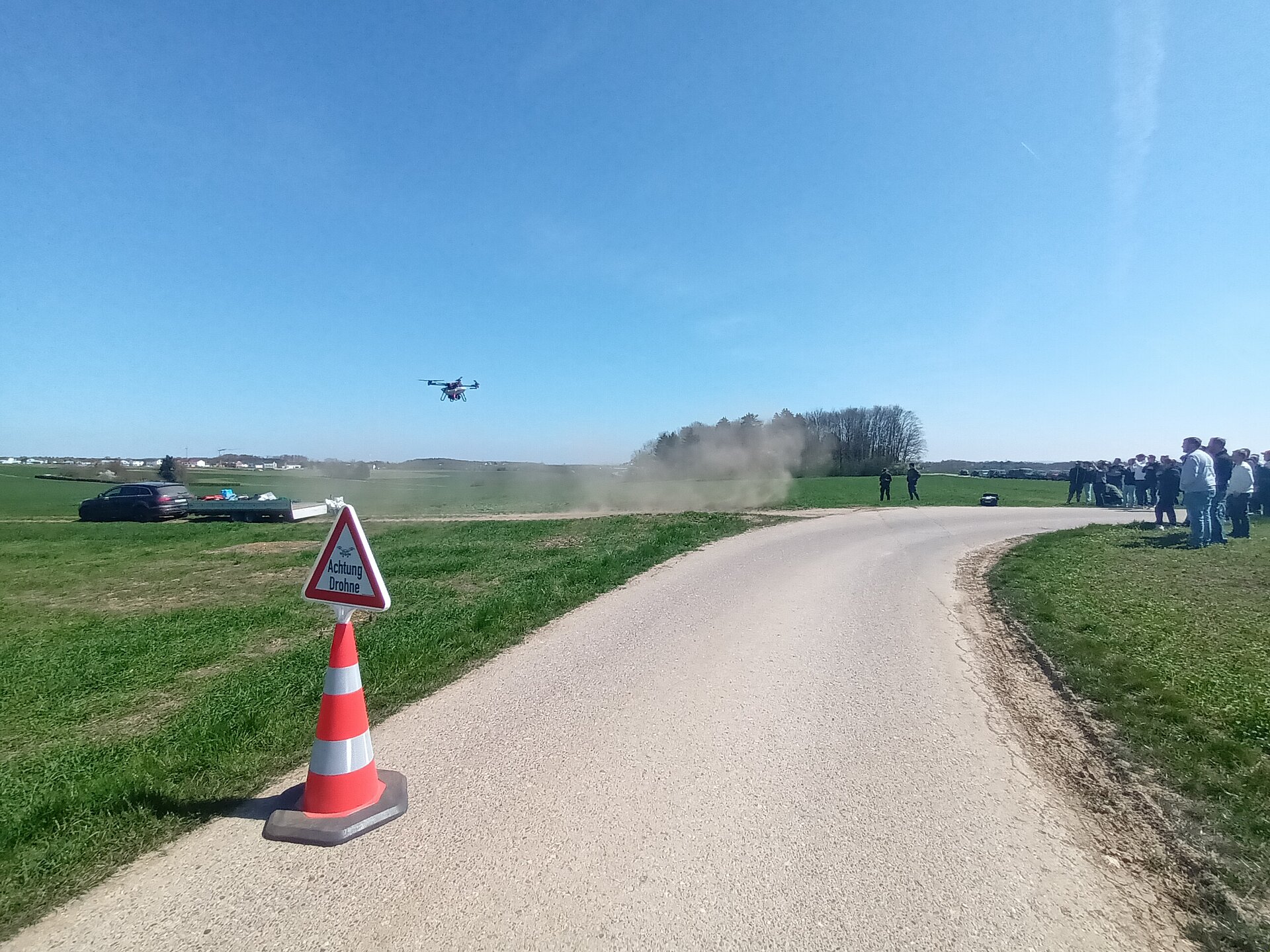 Drohnensaat über einem Acker, in Vordergrund ein Feldweg.